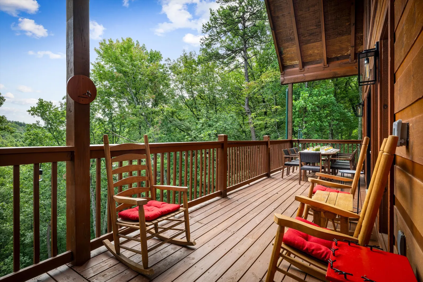 Wooden rocking chairs with red cushions along the covered deck at Acorn Ridge
